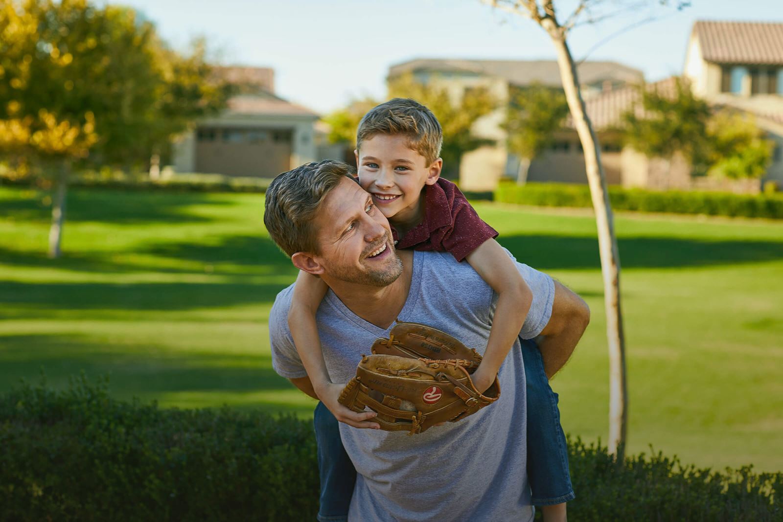 Father and son playing catch at park within the Alamar community in Avondale, AZ